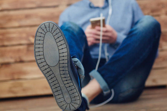 Cropped image of a young guy sitting on the floor listening to music on headphones. Image with depth of field