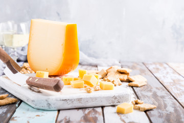 Delicious dutch gouda cheese with cheese blocks, crackers and special knife on old wooden table.