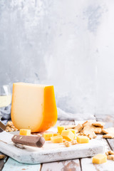 Delicious dutch gouda cheese with cheese blocks, crackers and special knife on old wooden table. - obrazy, fototapety, plakaty