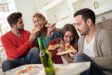Young people resting with pizza and drinks.