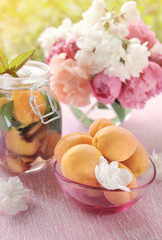 Obraz na płótnie Canvas Apricots in a transparent vase with a detox drink made from mint and apricots with a bouquet of peonies.