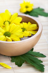 Obraz na płótnie Canvas Yellow flowers in wooden bowl