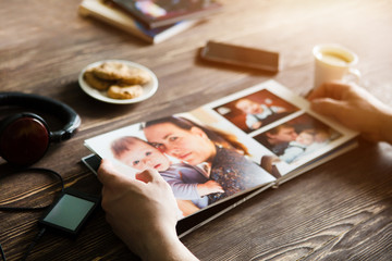 the Hand man holding a family photo album  against the background of the a wooden table
 - obrazy, fototapety, plakaty