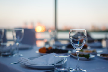empty glass for wine almost a wooden table, on background of the sea, sunset sky and folded umbrellas