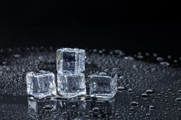 Wet ice cubes and water drop on black background.