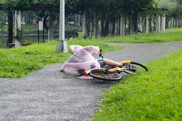 A boy wearing a raincoat and riding in the rain fell to the ground.