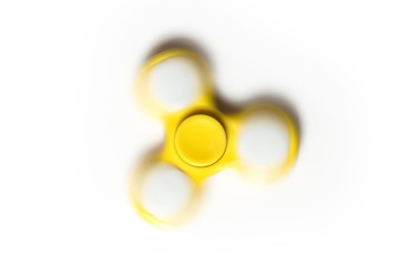 Yellow fidget spinner in motion against white background