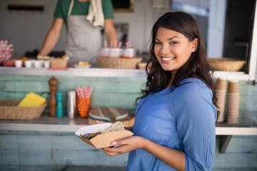 Smiling woman standing with snacks at counter