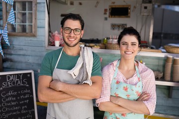 Portrait of waiter and waitress standing with arms crossed