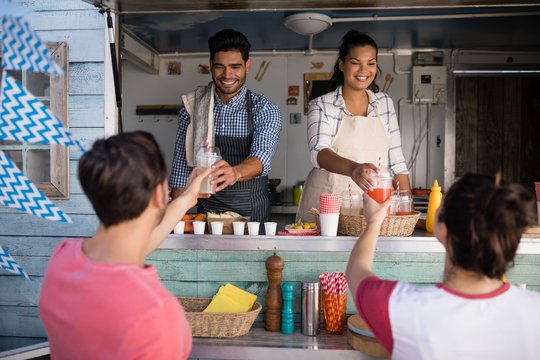 Waitress and waiter giving juice to customer at counter