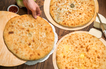 Baker's hands folded Ossetian pie on the table