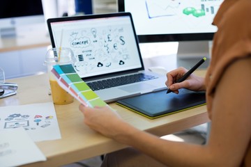 Female executive working over graphic tablet at her desk