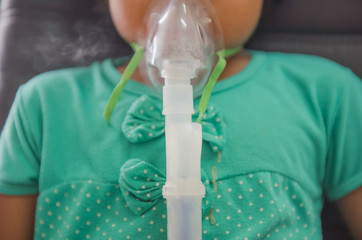 Young woman doing inhalation nebulizer with smoke from oxygen mask in the hospital.