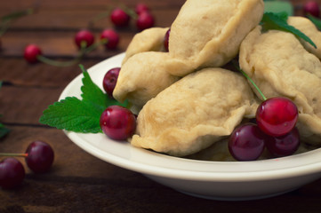 Homemade dumplings with cherries. Wooden rustic background. Close-up. Top view