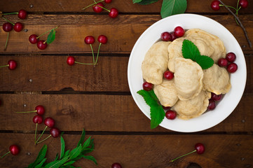 Homemade dumplings with cherries. Wooden rustic background. Close-up. Top view