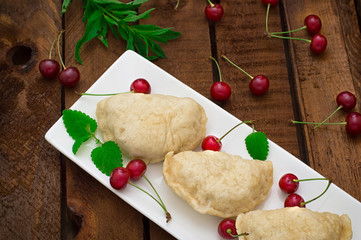 Homemade dumplings with cherries. Wooden rustic background. Close-up. Top view