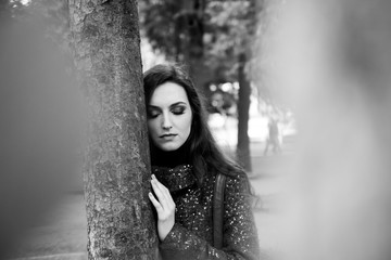 Amazing Brunette with Closed Eyes Standing near Tree in the Park. Black and White Portrait of Attractive Woman with Sensual Lips and Professional Makeup Outdoors.