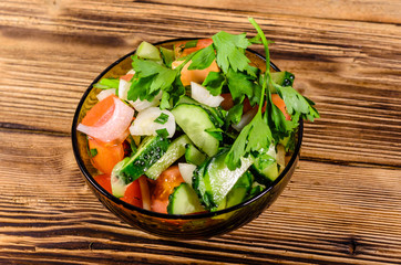 Salad with cucumbers and tomatoes on wooden table