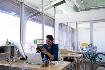 Male executive reviewing captured photograph at his desk
