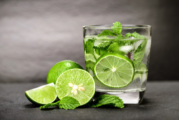Close up the fresh mojito cocktail with fresh lime and mint leaf on black stone background