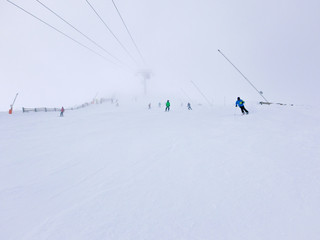 Fototapeta na wymiar Skiers in thick fog on ski slope in ski resort.