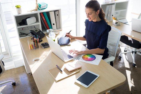 Female executive working over graphic tablet at her desk