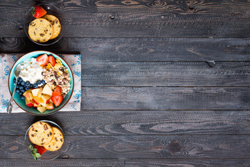 Healthy breakfast, cereal with yogurt, strawberries, blueberry, apple, banana, on rustic wooden.  Top view