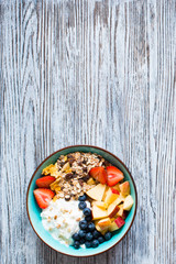 Healthy breakfast, cereal with yogurt, strawberries, blueberry, apple, banana, on rustic wooden.  Top view