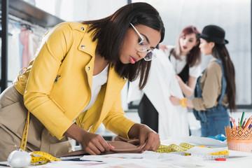 side view of confident fashion designer working with textile at workplace