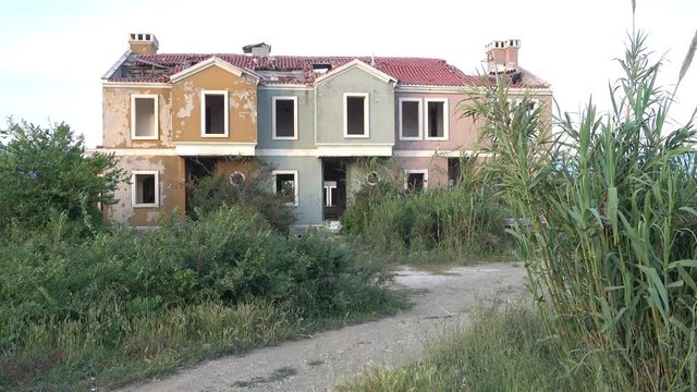 4K Run-down forsaken house without any windows in apertures, an overrun road
