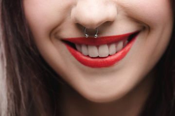 close up view of young girl with red lips and piercing in nose