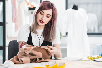 portrait of fashion designer working with textile in clothing store