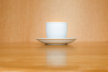 A white cup of coffee on wooden table.