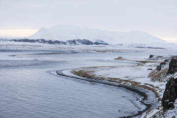 Breathtaking panoramic view on Vatnsnes peninsula, winter snowy frozen shore with the ocean and mountains on the background