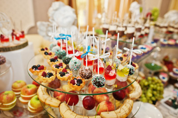 Gorgeous-looking wedding table with various beverages, delicious dishes, fruits and decorations.