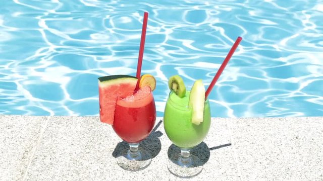 Cocktails on the background of the pool. Two fruit cocktails. Refreshing drink, fruit cocktail and pool.