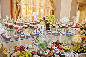 Gorgeous-looking wedding table with various beverages, delicious dishes, fruits and decorations.