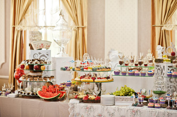 Gorgeous-looking wedding table with various beverages, delicious dishes, fruits and decorations.
