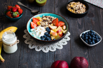 Healthy breakfast, cereal with yogurt, strawberries, blueberry, apple, banana, on rustic wooden.  Top view