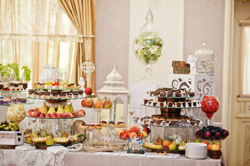 Gorgeous-looking wedding table with various beverages, delicious dishes, fruits and decorations.