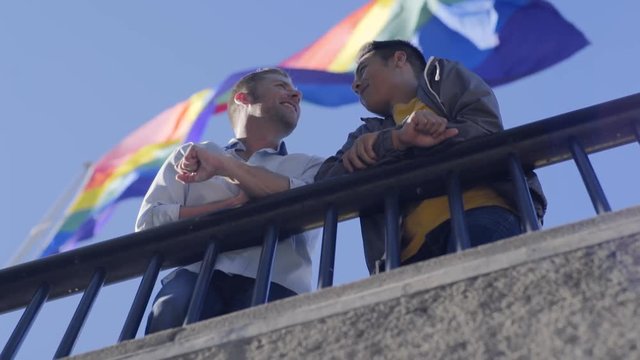Gay Couple Hold Hands, Stand Under Huge Gay Pride Rainbow Flag 