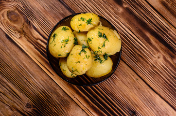 Boiled young potatoes in glass bowl on wooden table. Top view