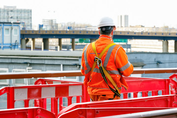 Back view of a construction worker walking into a building site in Canary Wharf