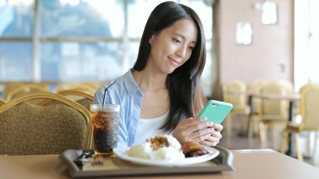 Woman using cellphone with her lunch in restaurant