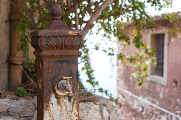 Fototapeta na wymiar Old rusty water column in Forza d'Agro, Sicily