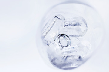 Pair of golden wedding rings with diamond in glass of ice cubs. Symbol of love, marriage or cooling of relations.