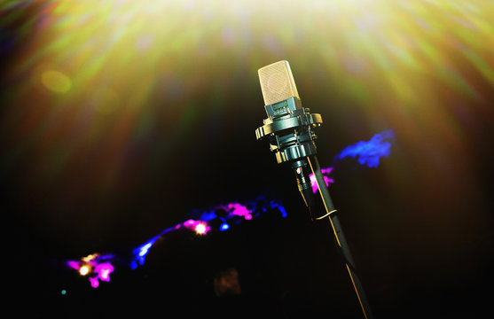 Microphone with golden rays of light. Retro microphone. A microphone on stage. A pub. Restaurant. Classic. Evening. Night show. European restaurant. European bar. American restaurant. American bar.