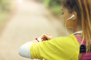 Woman jogging in the forest and setting smart watch