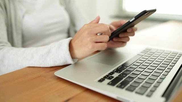 Woman using cellphone with laptop computer 