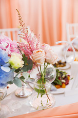 Table set for wedding banquet with floral composition of roses and astilbe. Flower decoration in vase.